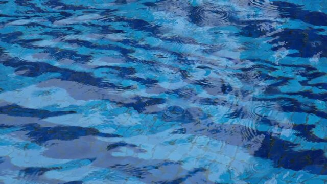 4k Tilting Footage Of Heavy Rain Falling In An Outside Blue Tiled Swimming Pool