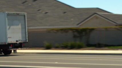 Home moving and shipping company white box truck driving down a road to its destination in 4K - panning shot