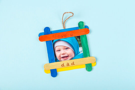 DIY and kid's creativity. Step by step instruction: how to make photo frame of ice cream sticks. Step5 insert baby's photo into finished frame. Children craft for Fathers Day.