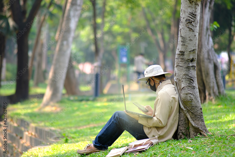 Poster man using laptop computer in garden background and technology concept