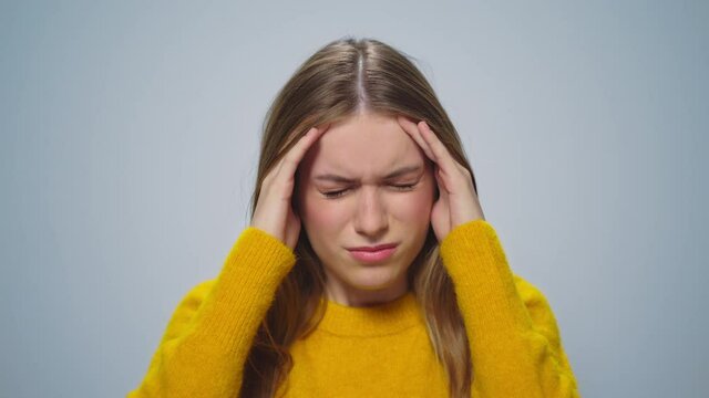 Closeup worried woman touching head with hands at camera on grey background.