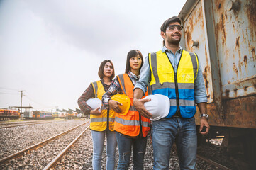 Obraz na płótnie Canvas Team engineer holding helmet standing in row on site work at train garage, banner cover design.