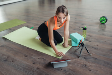 Young woman practicing yoga, is engaged with the teacher online.