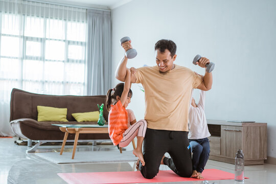 asian father use his child as weight for lifting exercise at home