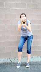 Female trumpet player blowing her horn outdoors.