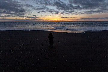 A woman takes a picture of the sunset at the beach in Puerto Naos (Canary Island, Spain)