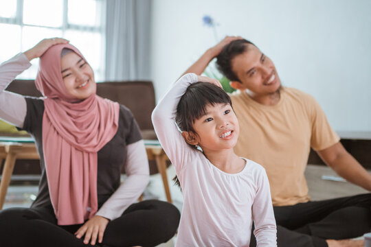 parent and kid doing exercise together. portrait of healthy muslim family workout at home
