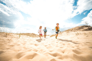 Father with two little kids boy and girl in the desert. Children running and playing