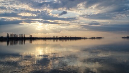 Fototapeta premium sun and clouds reflecting in the water of the Vistula river in Płock during the sunset