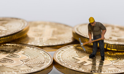 single miner working on a stack of bitcoins with gray background