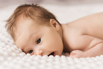 Portrait of a cute 6-month-old baby, a newborn naked girl lying on the bed