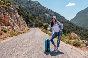 Girl traveler in nature with a suitcase