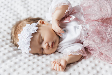 Portrait of a cute 6-month-old baby, a little girl in baby clothes in a crib