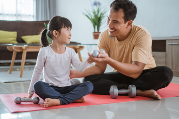 happy father and daughter exercising doing dumbbell lifting together in the livingroom