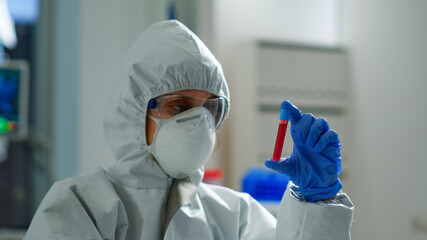 Fototapeta na wymiar Biochemist in coverall holding blood sample analysing chemical reaction working in medical lab. Scientist examining vaccine evolution using high tech for treatment development against covid19 virus