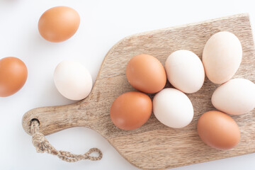 white and brown eggs lie on a wooden board on a white table. home life. The process of preparing...