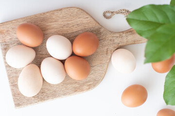 white and brown eggs lie on a wooden board on a white table. home life. The process of preparing for Easter.
