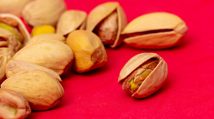 Close-up of fresh pistachio nuts on a red background.