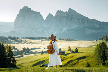 Young boy in hat and plaid shirt looking at the beautiful green valley of Alpe di Siusi, Dolomites.
