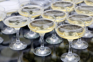 Glasses with white sparkling wine, champagne are reflected in glass table. Concept of celebration, evening party, reception