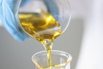 Researcher drains golden liquid into chemical flask