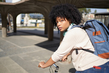 Latina woman riding a bicycle in the city. African American woman using green transportation 