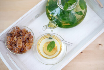 Fresh brewed mint tea on tray with teacup teapot and candi sugar healthy living