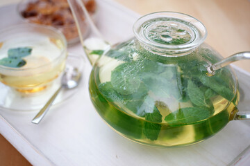 Fresh brewed mint tea on tray with teacup teapot and candi sugar healthy living