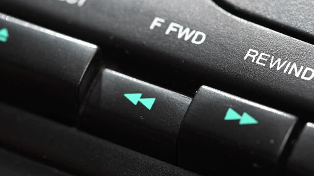 Pressing a button on a vintage tape recorder. Close-up. A person s finger presses the playback control buttons on an audio cassette player. Macro. rewind button