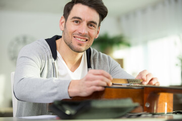 happy man using a screw driver on a guitar
