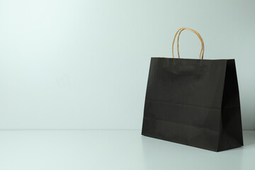 Black paper bag on white background, space for text