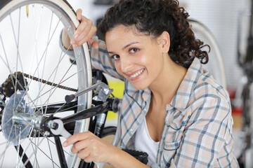 happy woman bicycle engineer repairing a bike in workshop