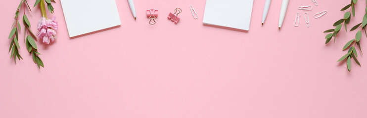 Workspace with notepad, pen, paper clips, eucalyptus and hyacinth on pink background