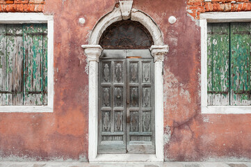 Old vintage facade of the house with door and window. Medieval architecture in Venice, Italy.