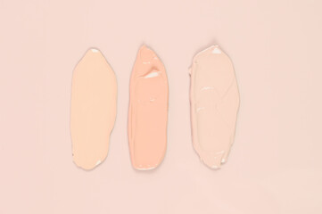  Makeup product smears on pink background. Color set of foundation, top view