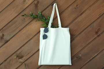Eco bag with twig and sunglasses on wooden background