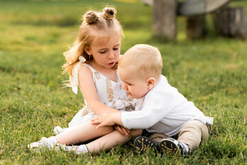Cute little girl playing with her brother outside on a sunny day