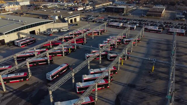 TTC public transit buses at large operations, maintenance and storage facility as multiple buses drive through parking lot; aerial