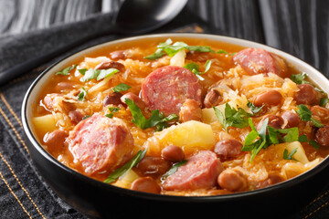 Sauerkraut stew with borlotti beans, potatoes and sausages close-up in a bowl on the table. horizontal