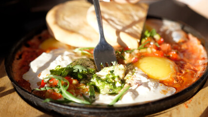 Eating Shakshuka Poached Eggs with Tomato and Bread Served in a Frying Pan. Israeli Arab Middle Eastern Cuisine. 4k
