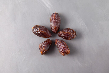 Five large Iranian dates on grey background. Natural substitute for sweets. Dried fruits contain many vitamins and trace elements