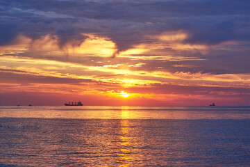 Sunset on the sea, ships standing on the horizon.