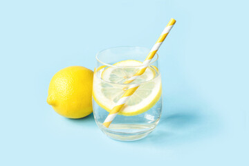 Glass of water with lemon on a blue background. Summer refreshing drink.