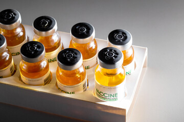 Vials with coronavirus vaccine in packaging on a black background and illuminated by a beam of...