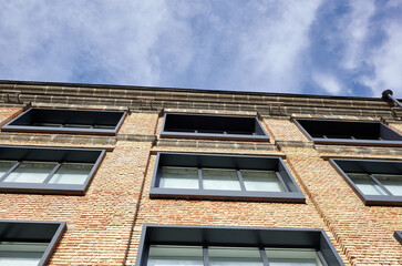 Fototapeta premium Brick building with windows and downspout against blue sky