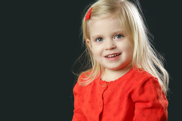 Studio portrait of beauiful blonde toddler girl in red cardigan