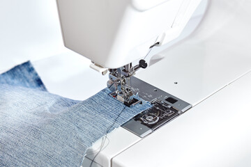 Sewing machine working part with blue denim cloth. A close-up shows a needle passing through tissue