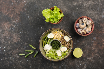 Vegetable bowl with lentils, string beans, sprouted peas, quail egg, soft cheese, fresh lettuce and sauce on a dark background.
