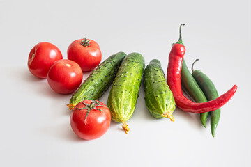 Tomatoes, cucumbers and hot chili peppers on a light background