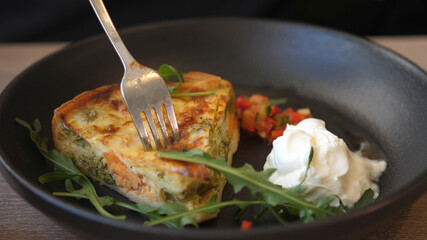 Man eats delicious French Quiche aux legumes and salmon in a pan - Vegetable quiche